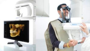 Dental professional using a wall-mounted X-ray machine with a patient seated in a dental chair, viewing results on a digital screen
