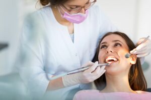 Dental hygienist examining patient's teeth in dental chair