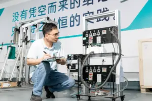 A technician inspects machinery in a factory setting, holding a clipboard and pen