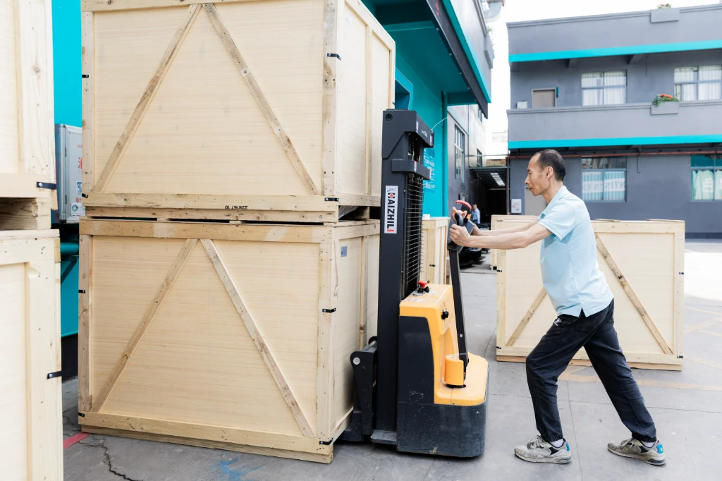 Man using forklift to transport dental equipment in wooden crates, ensuring quality and traceability.