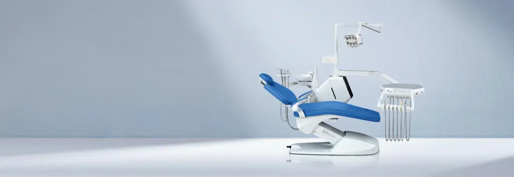 A sleek and modern dental chair in a bright, spacious dental office, with a blue seat and various dental instruments attached