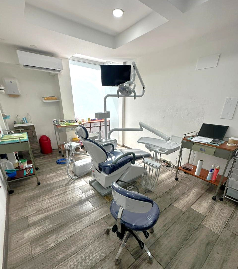 临床牙科手术室,配有可调节牙科手术椅和移动式牙科设备推车,置于顶置手术灯下