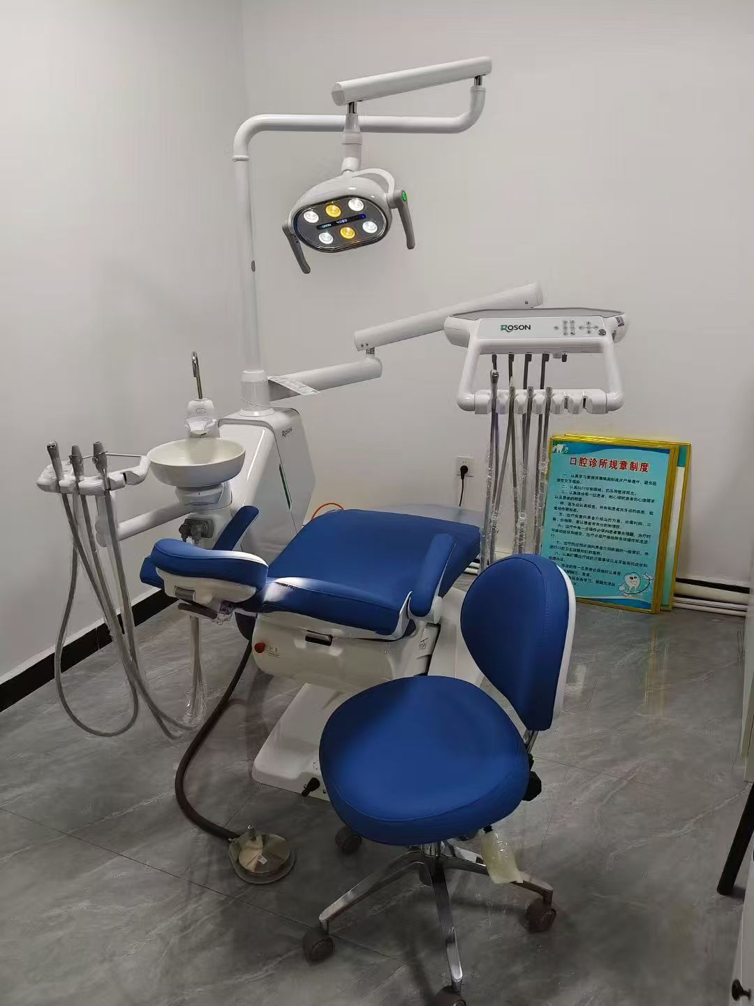 A dental air compressor is neatly installed in a clean, well-lit basement utility room, far from the patient treatment areas.