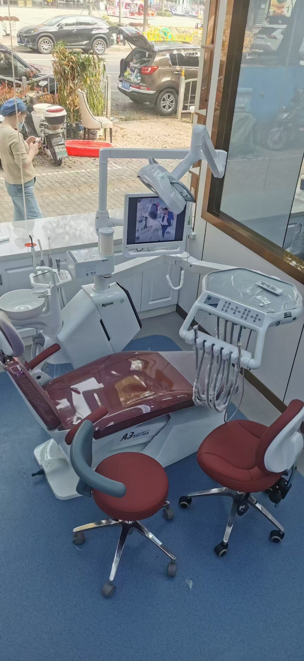 A dental assistant pouring distilled water into a modern tabletop autoclave in a clean, well-organized sterilization room.